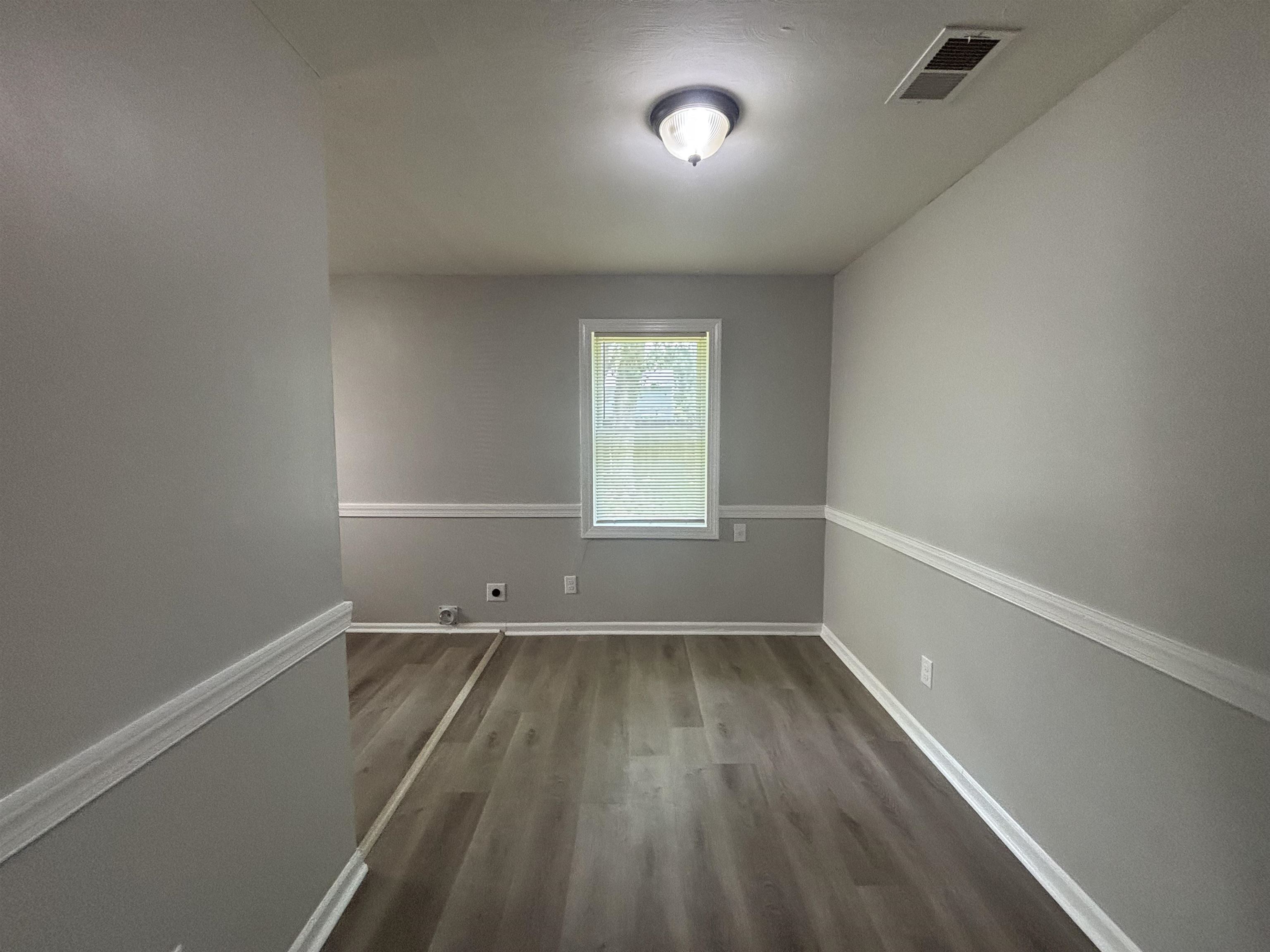 2591 Callie Road Memphis, TN 38127 - Photo 5 of 13 Interior room featuring wood-finish flooring, light gray walls with white chair rail molding, and a single window