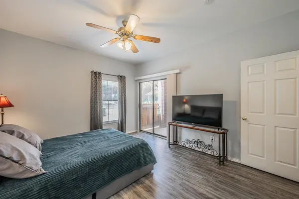 a bedroom with a large bed a flat tv screen and a chandelier