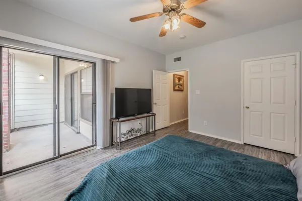 a view of a livingroom with a flat screen tv wooden floor and a ceiling fan