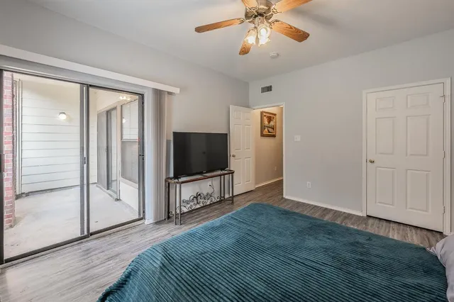 a view of a livingroom with a flat screen tv wooden floor and a ceiling fan