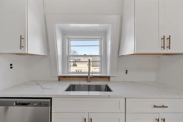 a kitchen with white cabinets and a window