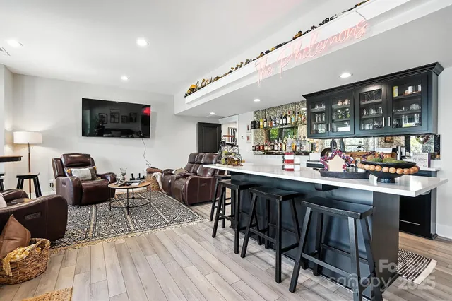 a living room with stainless steel appliances kitchen island granite countertop a table chairs and a wooden floor