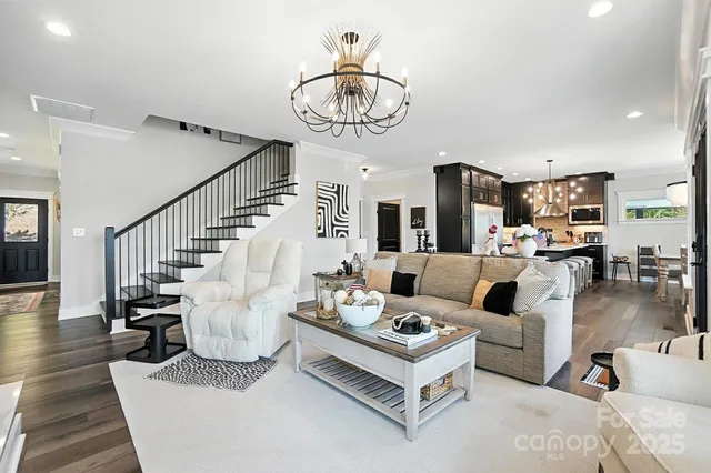 a living room with furniture a chandelier and a dining table with wooden floor
