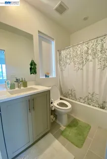a bathroom with a granite countertop toilet a sink a mirror a shower a vanity and a window