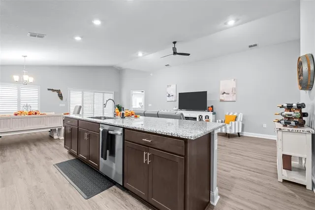 a kitchen with stainless steel appliances kitchen island granite countertop wooden floors and white cabinets