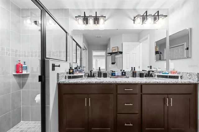 a bathroom with a granite countertop sink a toilet a mirror and shower