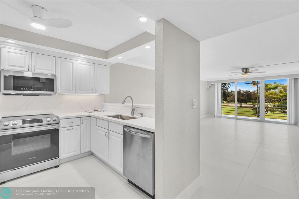 3800 Oaks Clubhouse Drive, Unit 201 Pompano Beach, FL 33069 - Photo 23 of 29 a kitchen with a sink stove and cabinets