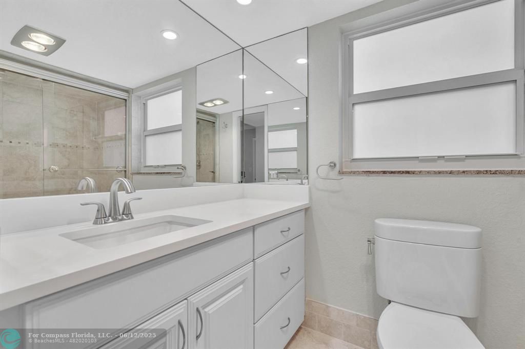 3800 Oaks Clubhouse Drive, Unit 201 Pompano Beach, FL 33069 - Photo 9 of 29 a bathroom with a toilet a sink and mirror