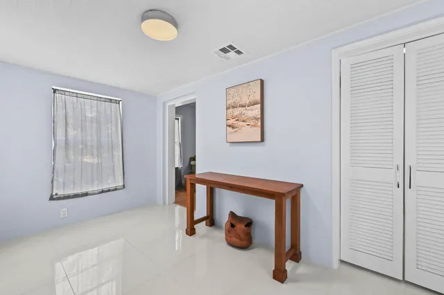 a view of an empty room with window and closet area