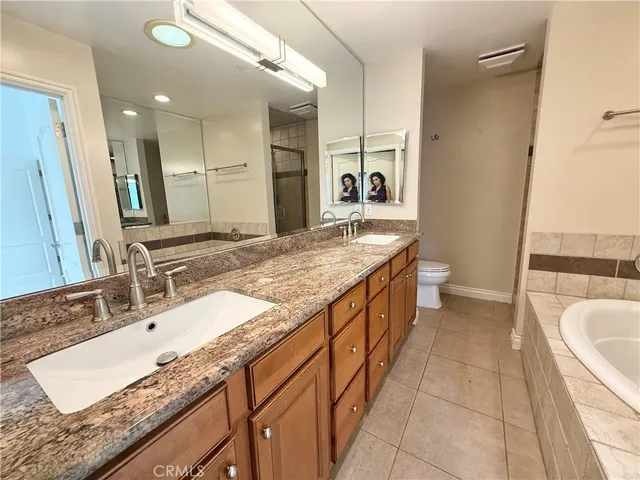 a spacious bathroom with a granite countertop sink a large mirror and a bathtub