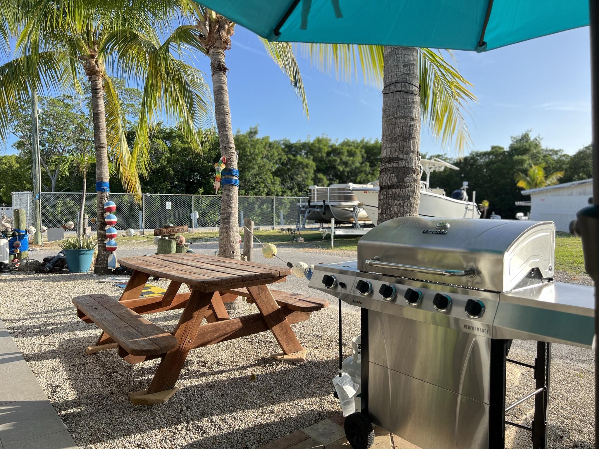 325 Calusa Street, Unit 245 Key Largo, FL 33037 - Photo 10 of 48 a backyard of a house with barbeque oven table and chairs