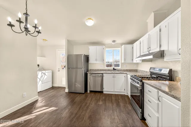 a kitchen with a refrigerator a sink dishwasher a stove and white cabinets with wooden floor