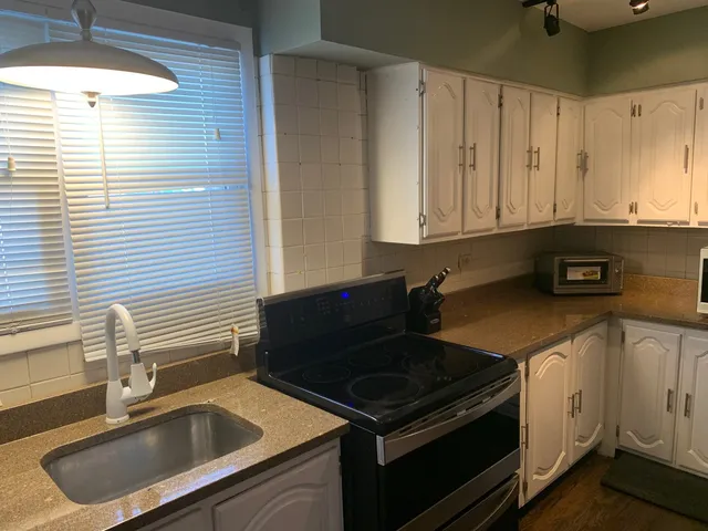 a kitchen with granite countertop a sink stove and cabinets