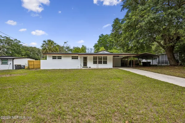 a front view of house with yard and trees in the background