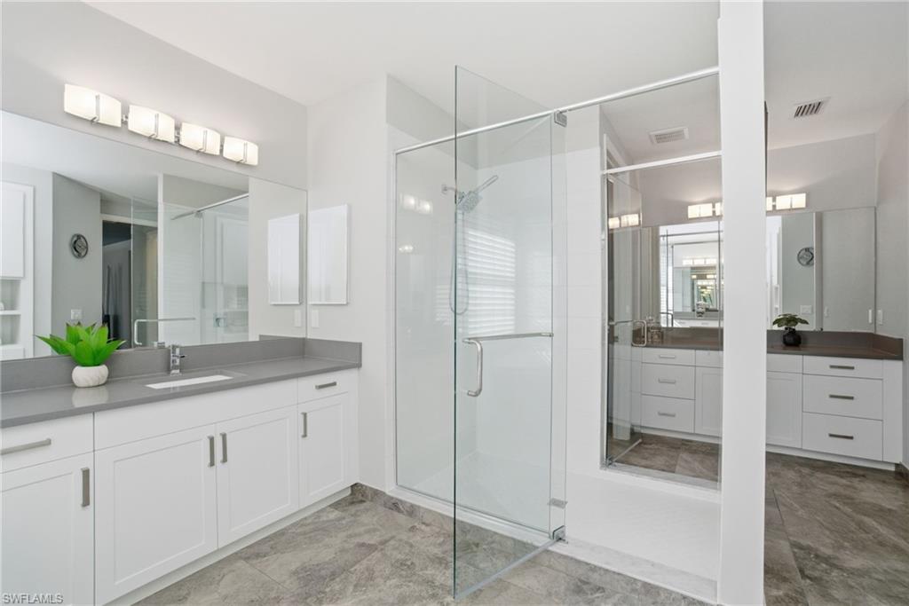 4654 Kensington Circle Naples, FL 34119 - Photo 19 of 48 a bathroom with a granite countertop sink mirror and shower