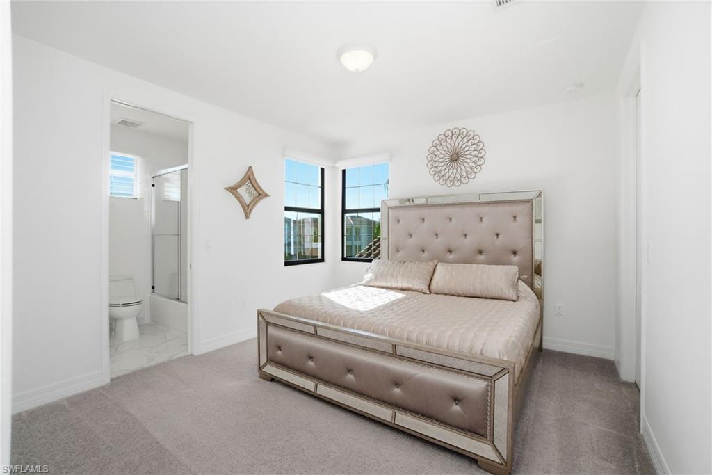 4654 Kensington Circle Naples, FL 34119 - Photo 20 of 48 a bedroom with a bed and a chandelier