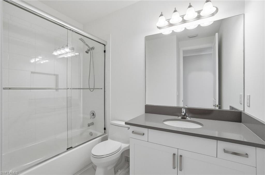 4654 Kensington Circle Naples, FL 34119 - Photo 24 of 48 a bathroom with a sink vanity granite toilet and a mirror