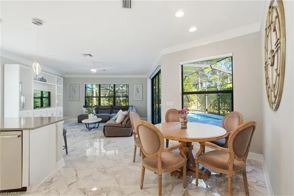 a kitchen with stainless steel appliances granite countertop a dining table chairs and sink