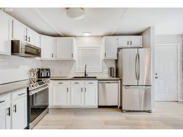 a kitchen with stainless steel appliances granite countertop a refrigerator a stove a sink and white cabinets