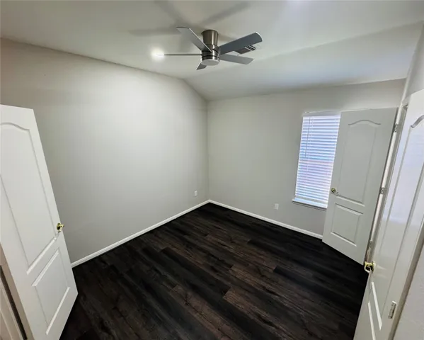 a view of an empty room and wooden floor and a ceiling fan