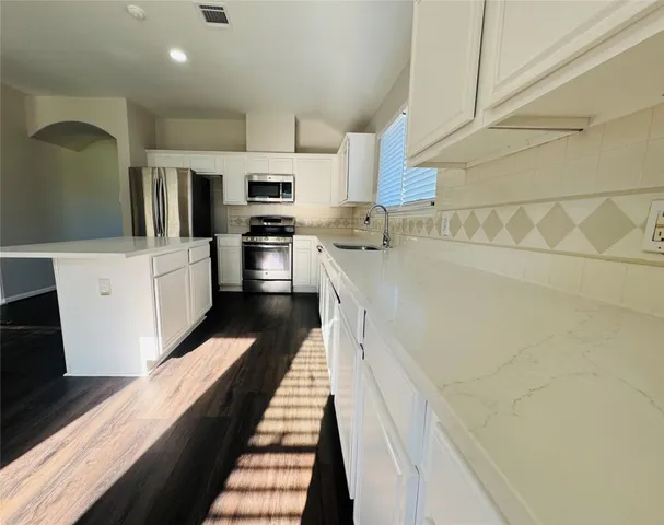 a kitchen with white cabinets and stainless steel appliances