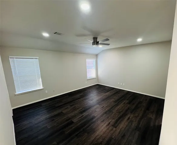 an empty room with wooden floor and windows