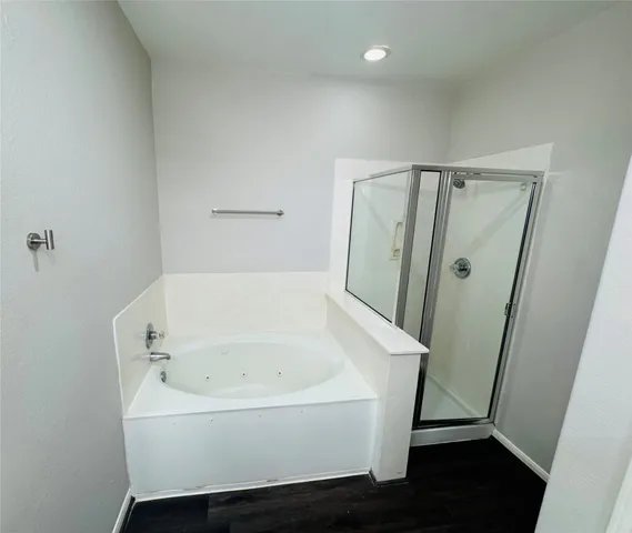 a bathroom with a tub a mirror and a shower