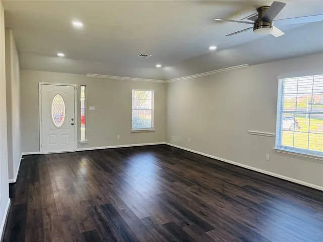 an empty room with wooden floor and windows
