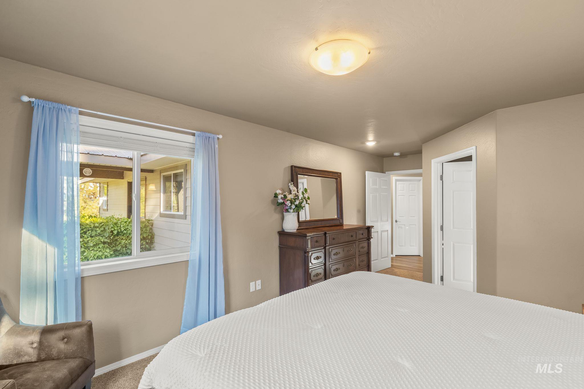 435 River Pointe Lane Lenore, ID 83541 - Photo 18 of 50 Carpeted bedroom featuring a dark wood bed frame, two wall-mounted sconces, and a ceiling light fixture