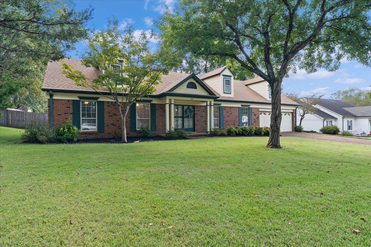 New england style home with brick siding, a porch, roof with shingles, an attached garage, and driveway