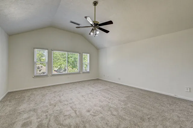 an empty room with windows and ceiling fan