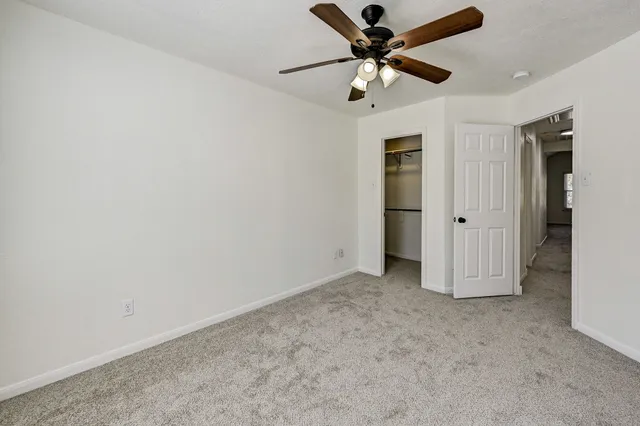 an empty room with closet and a ceiling fan