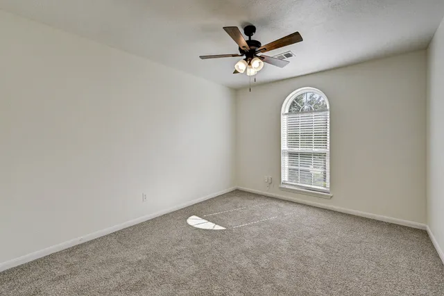 an empty room with windows and fan