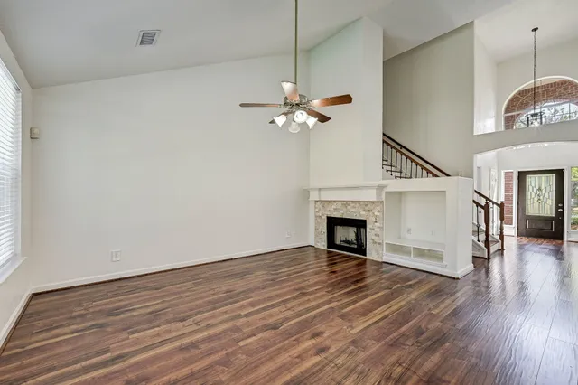 a view of a livingroom with a fan a fireplace a ceiling fan and wooden floor