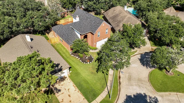 an aerial view of a house with a yard and trees all around