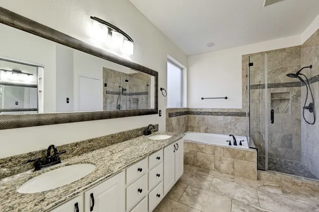 a bathroom with a granite countertop tub sink and mirror