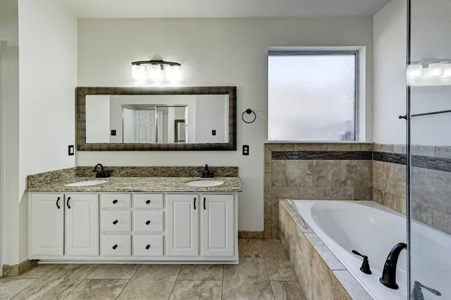 a bathroom with a granite countertop sink a mirror and a bathtub