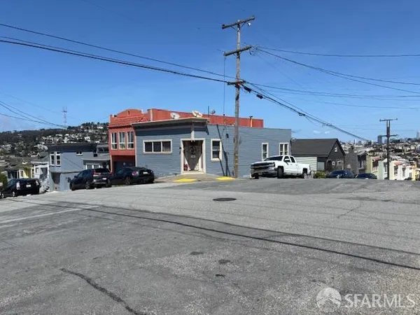 a view of a building with a cars park side of road