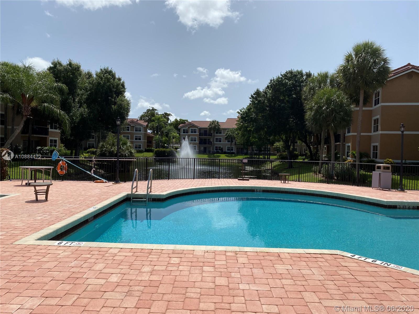 8741 Wiles Road, Unit 204 Coral Springs, FL 33067 - Photo 17 of 22 a view of a swimming pool with a lawn chairs under an umbrella