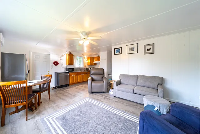 a living room with furniture and a dining table with wooden floor