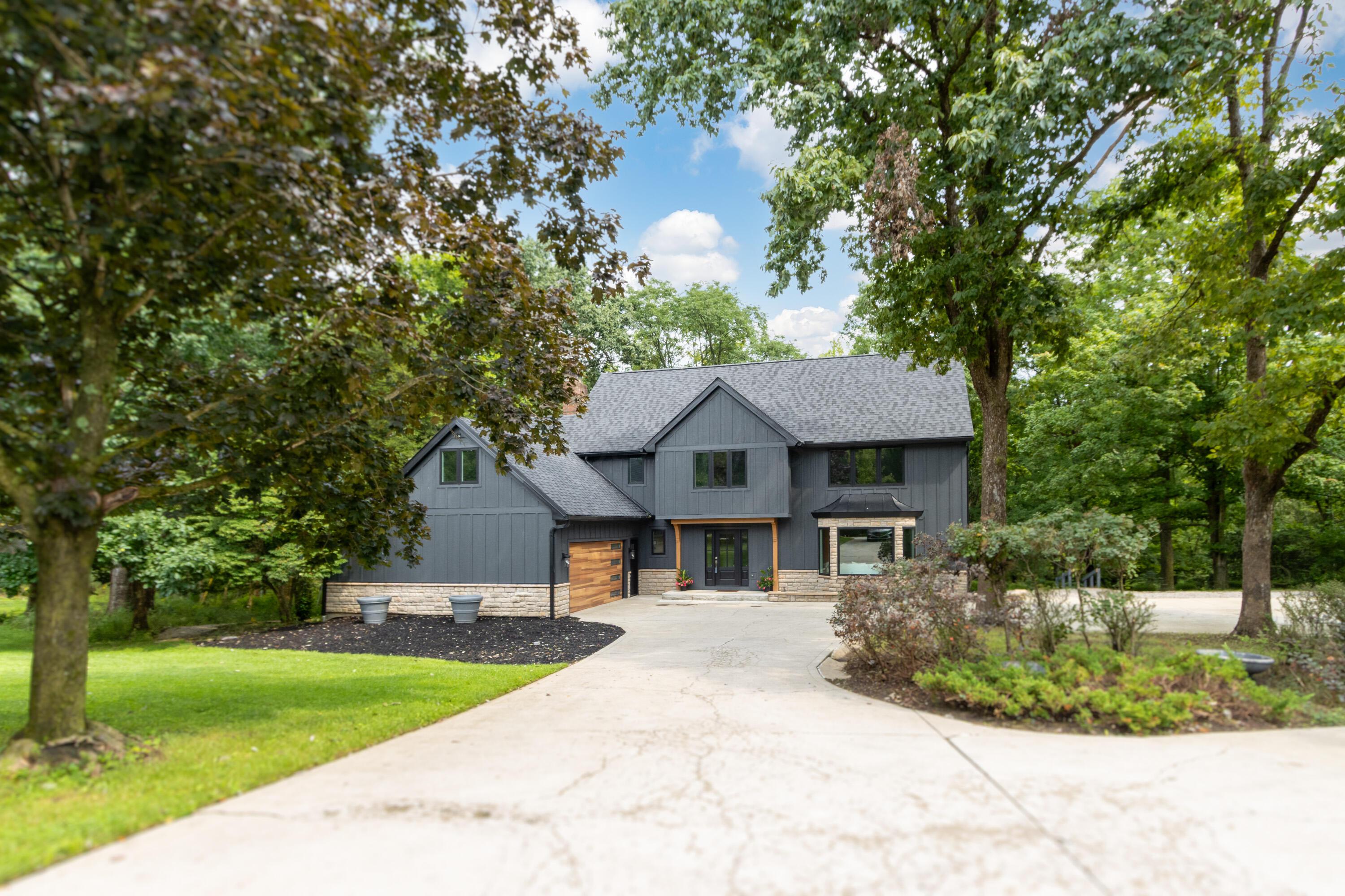 1560 Carriage Road Powell, OH 43065 - Photo 9 of 73 Dark gray exterior with board and batten siding, stone accents, and a wood-finish garage door