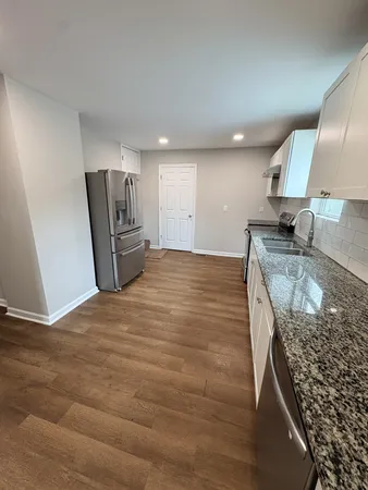 a kitchen with granite countertop a sink a stove a refrigerator and blue cabinets