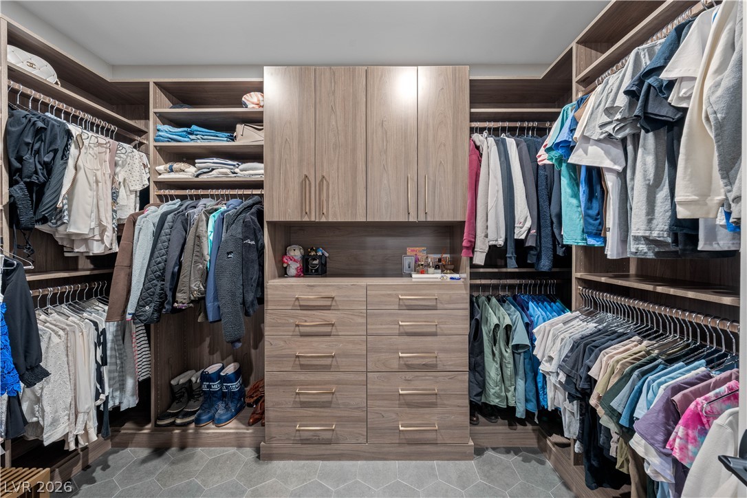 9719 Starlight Ridge Avenue Las Vegas, NV 89148 - Photo 14 of 25 An organized walk-in closet boasts ample storage with custom cabinetry and abundant hanging space.