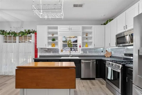 a large kitchen with a fireplace and wooden floor