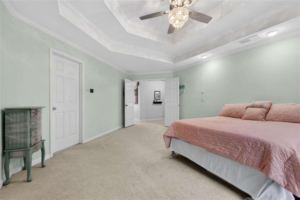 230 Gaelic Way Tyrone, GA 30290 - Photo 31 of 53 a spacious bedroom with a large bed and a chandelier