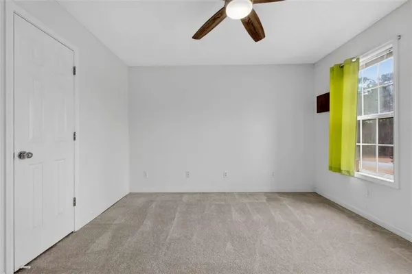 an empty room with windows and fan