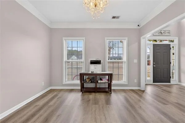 a view of an empty room with a window and wooden floor
