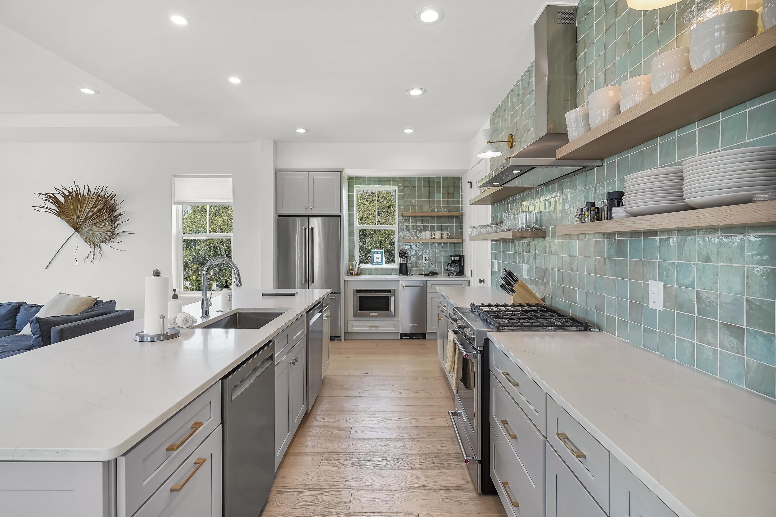 104 7th Street St. Augustine, FL 32080 - Photo 10 of 59 Kitchen with gray cabinets, stainless steel appliances, open shelves, recessed lighting, and a large island with sink