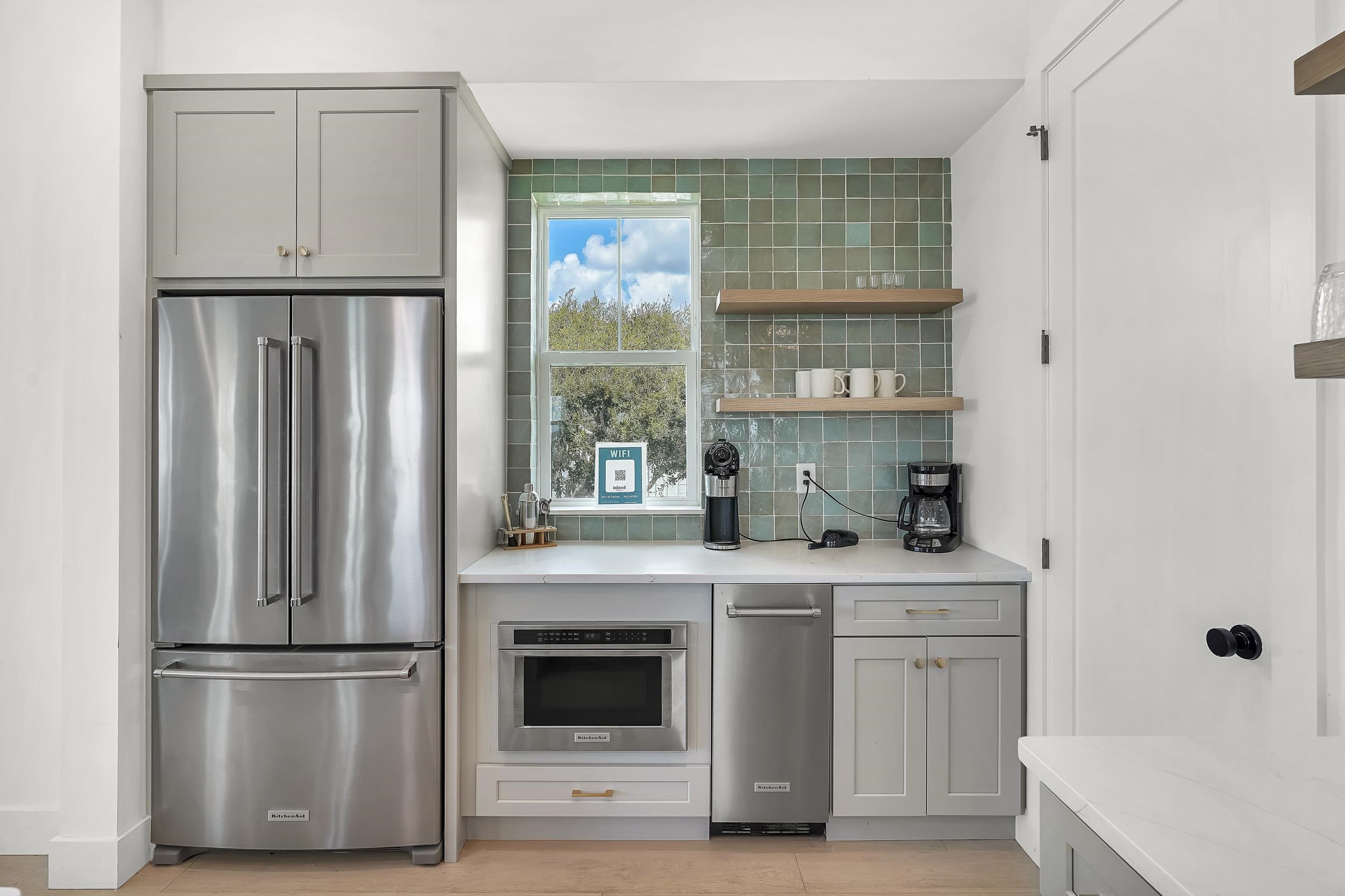 104 7th Street St. Augustine, FL 32080 - Photo 12 of 59 Kitchen featuring gray cabinets, freestanding refrigerator, open shelves, backsplash, and light stone countertops