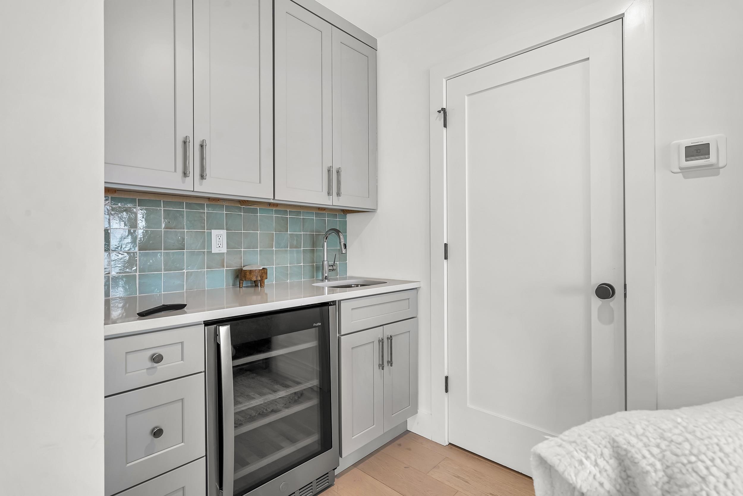 104 7th Street St. Augustine, FL 32080 - Photo 26 of 59 Indoor wet bar with beverage cooler, gray cabinets, light wood-type flooring, tasteful backsplash, and light stone countertops